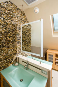 HighCraft-Builders-green-solid-surface-vanity-top-with-pebble-wall-and-floating-mirror