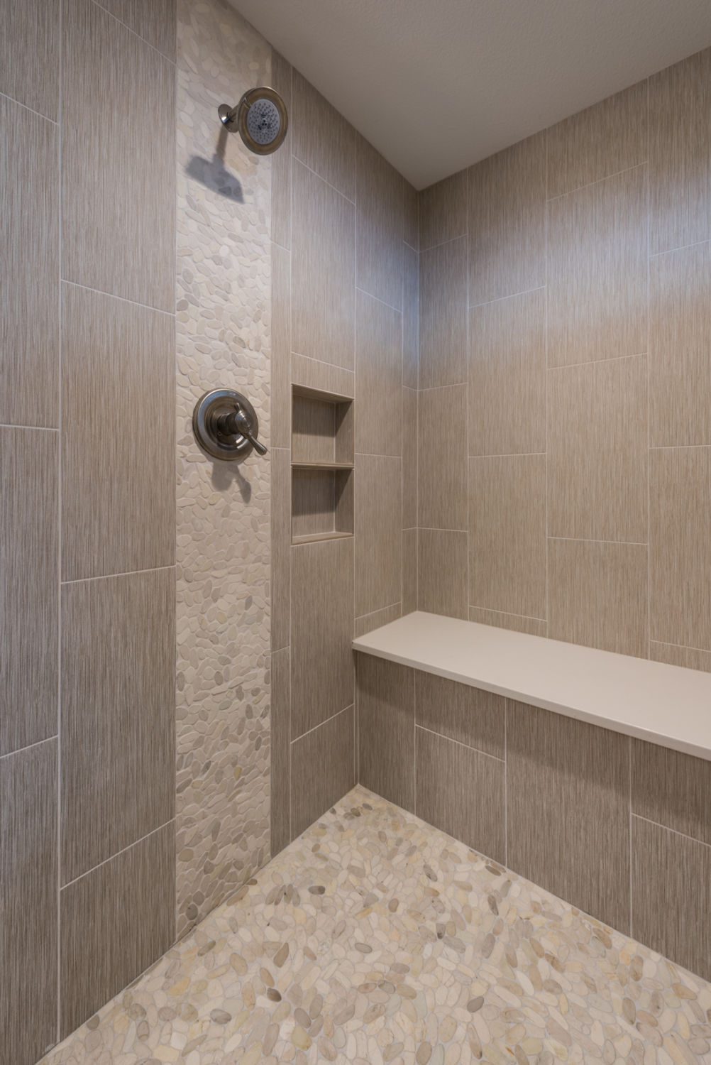 Spa-like-shower-with-bench-seat-in-ranch-style-custom-home-with-pebble-poured-pan