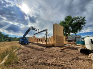 custom_home_construction_fort_collins_co_early_framing_blue_forklift_holding_beam
