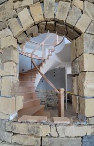 whole-house-remodel-curved-stairs-stone-wall-window